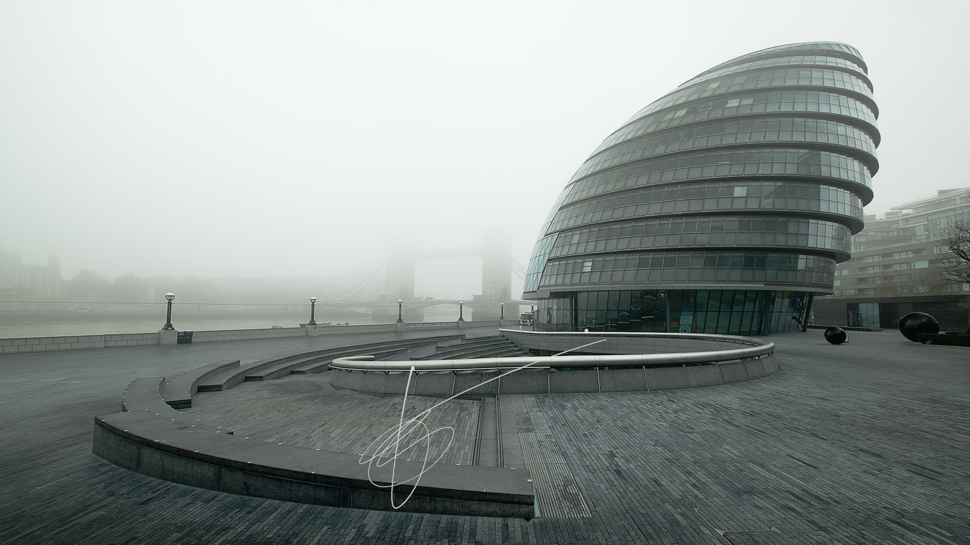 The area of City Hall in London, with Tower Bridge hidden behind the fog on the background
